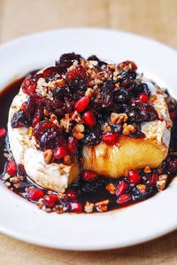 Baked Brie with Cranberries, Pecans, Pomegranate on a white plate