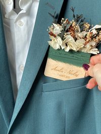 Looking for a pocket buttonhole for the groom? Combining dried flowers, wood and personalization, this buttonhole is the original accessory to slip into the suit pocket that is sure to please the future groom! Very trendy, it will complete the gentleman's suit with its floral side and becomes a real element of the outfit of the groom and his witnesses. > DESCRIPTION: Engraved wooden pocket buttonhole decorated with dried and preserved flowers > SIZE: Approximately 8 x 13 cm with flowers It fits most adult costume pockets If necessary, the dimensions can be adapted (especially for a child's costume) > CUSTOMIZATION To personalize with the text of your choice: declaration of love, first names/nicknames, date... It is possible to create a model with personalized flowers in the colors of your