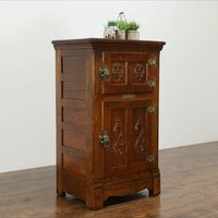 A solid oak farmhouse kitchen pantry "ice box" was the refrigerator of its day, chilled with a block of ice. Dating from about 1890, the brass maker's signature reads "Belding's New Perfection." This solid oak cabinet has it original tin lining. Panels and carving are authentic, embossed brass hardware is original.

The restored finish is in excellent condition on this antique American made furniture.

Size is 31 1/2" wide, 22" deep and 52 1/2" tall.