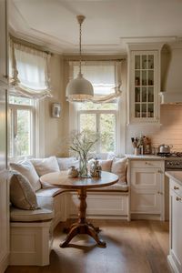 Small breakfast nook with a round table, bench seating, and light curtains