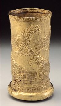 The shape and proportions and even the reinforced rim of this beaker resemble those of the vessel discussed in catalogue number 21. This beaker is also made in two pieces, the cylindrical part and the bottom. The outside of the beaker is decorated with two rows of raptors, or birds of prey: Those in the upper register face toward the viewer's right, and those in the lower row, to our left. The forms are rendered in low relief, raised only slightly from the plain ground. Each bird has a hooked be