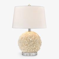 Bring a stunning coastal aesthetic to your home with this incredible table lamp. Exquisitely crafted with beautiful, natural, off-white shells surrounding the elegant round base, the charming texture and beach vibe perfectly complements the luxurious, crisp white shade and elegant silver tones of the base.