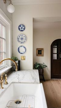 a neutral kitchen with refined gold fixtures and a lovely mini plate wall with chinoiserie plates for a lovely and refined touch