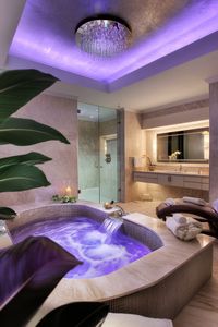 Indulge in the elegance of this modern bathroom design featuring a stunning jacuzzi with soothing purple lighting and a chic chandelier. Perfect for relaxation and rejuvenation. #ModernBathroomIdeas #LuxuriousLiving #HomeDecor