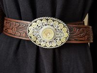 NEW! We now offer a smaller size oval buckle that embraces the style and wow factor of our BEST SELLING larger oval belt buckles. For those that want a smaller belt buckle or for ladies that want to wear our buckle designs, this slightly smaller buckle is the perfect choice! Buckle features a bed of brass 9mm bullet casings embellished with a combination of detailed filigree and topped with a 12 gauge shotgun casing set in our signature rope bezels. Brand of 12g varies. We use old Winchester Wes