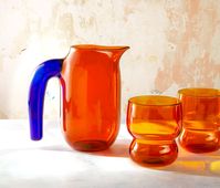 Set of 3: 1 Pitcher & 2 Tumblers (Select your glass color.) Create a fun & modern art-house expression for your next beverage or wine experience with this the Rhythm Colour Borosilicate Petite Carafe/Tumblers Set of 3-including 1 Amber & Cobalt Blue petite jug and your choice of either 2 Cobalt Blue or Amber matching tumblers.Each uniquely made, the organic piece is created using borosilicate glass (this means it will not crack under extreme temperature changes like regular glass- and is more du