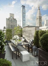 An aluminum bench and table by Harbour Outdoor and lanterns by Restoration Hardware sit on a terrace outside of a New York City terrace.