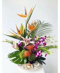 Bring the blissful vibes of a day at the beach to someone's day with this elegant and striking floral design. Featuring a selection of tropical flowers and foliage, including orchids, red ginger, and protea, this arrangement captures the...