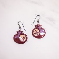 Adorn yourself with these unique, hand-painted ceramic pomegranate earrings. Perfect for adding a touch of sophistication to any outfit, they boast a beautiful, timeless quality that is sure to elevate any ensemble to the height of elegance.