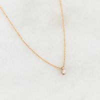 A classic round diamond pendant on a dainty 14k gold chain. This versatile necklace has a place in any woman’s wardrobe, and can make a wonderful gift for a special woman in your life. 1 round lab grown diamond with a width of 1.7mm 0.019 total carat weight Bezel setting Necklace has an adjustable length and can be worn at 16", 17" and 18"