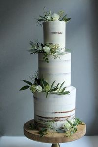 Minimal semi-naked tall three tier cake. Simple white and green wedding cake.