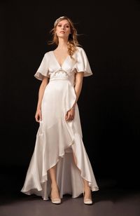 Satin wedding dress with bias cut ruffled panels and wide waistband with crystals and soft satin bow on lower back by Temperley Bridal.