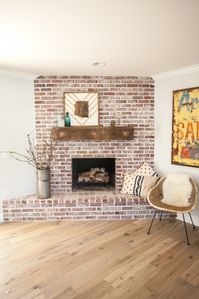 Custom brick fireplace with antique white mortar and custom reclaimed barn wood mantel - as featured on 'Rafterhouse' pilot episode on HGTV.