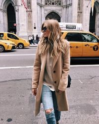 Camel tan wool winter coat, tan beige oatmeal sweater, light distressed jeans. Cute casual fall street style outfit inspiration ideas.