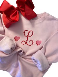 This girls monogrammed Valentine's Day sweatshirt is adorable featuring a scalloped initial with two tones hearts embroidered on either side.