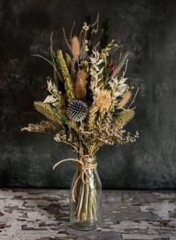 A beautiful selection of wild, rustic flowers arranged by a traditionally trained florist.  This handtied arrangement of naturally dried flowers comes in a range of colours, other options are available on our shop. As this is a natural product, colours and contents may differ slightly from product image to reflect seasonal availability.   Milk bottle is 14cm high by 7cm wide. Including flowers the overall arrangement stands approximately 35cm high by 16cm wide.  Please note: these are not design