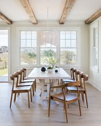 Modern wood dining chairs + white dining table + rustic wood beams in the dining room + large windows and a woven white chandelier | Scout & Nimble