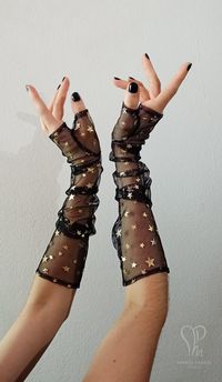 Limited edition! This pair of fingerless gloves is made of tulle with gold foil stars and feature a separate thumb. They're perfect to grade up any witchy, goth or evening look. ** SIZE INFORMATION ** Please select your preferred size from the bar: - Small - wrist contour: 16cm or 6 1/4'' - Medium - wrist contour: 18cm or 7'' - Large - wrist contour: 19.5cm or 7 3/4'' ** CARE INSTRUCTIONS ** Spot wash only -this will prevent early damage on the stars foil. It's highly recommended to use your hai