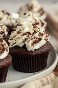 Chocolate cupcake topped with white frosting and chocolate shavings.