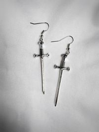 One pair of sword earrings. Features an earring hook and comes with rubber backers. Sword is approximately 2 inches long. Earring hooks are hypoallergenic silver plated alloy.