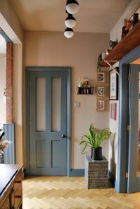 The doorway to a kitchen with a blue-trim accent next to a small gallery wall of framed art.