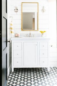 black and white bathroom, black and white tile, black door, pink and yellow, white marble, white shiplap, yellow flowers, white vanity cabinet, glass globe wall sconce, blush pink, bamboo mirror, yellow striped towels, towel ring, ochre, black and white, bright yellow