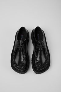 Black leather shoes with visible black stitching and chunky rubber outsoles.