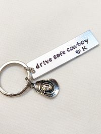 "Drive Safe Cowboy Hand Stamped 2\" Aluminum Blank with Cowboy Hat Charm Keychain ( leave your initial to personalize) Birthday, Valentine's Day, Western gifts, rancher keychain ++May change to \"Cowgirl\" or any other word you'd like++ (leave stamping changes in the personalization area during checkout) *Great Gift for any Man, Woman that loves Western Style Living!* Remind them to \"drive safe\" and add a small heart and initial to make it a custom gift Please leave exact stamping in the \"per