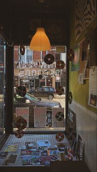 pictured from within is the storefront of pinwheel records, a vintage and modern vinyl record shop in pilsen, chicago, illinois. 📍 located on w 18th st, near the 18th Street Pink Line CTA train station. — brown aesthetic, vintage style, things to do in chicago, perusing pilsen, pilsen, el corazon de chicago, neighborhood record store, window shopping, record shopping, black girl at record store