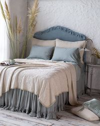 Adele Shams and Coverlet in Parchment, Frida Pillowcases, Bria Fitted Sheet, Bria Flat and Linen Whisper Bed Skirt in Eucalyptus. Taline 24x24 Square Pillow in Eucalyptus and Harlow 24x24 Square Pillow in Parchment on the floor.