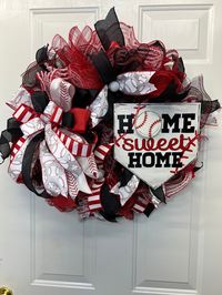 This Baseball wreath is made with black and red deco mesh, and has white baseball ribbons. It has a beautiful bow and a home plate wooden sign which has "Home Sweet Home" written on it.