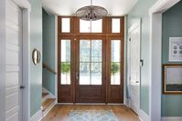 The handsome wood front door creates a stately entrance to the home while also bringing in ample sunlight. The cool green walls feel tranquil and refined to give the home entrance a timeless yet relaxed feeling.