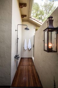 Morgan Harrison Home - An oil rubbed bronze vintage carriage lantern lights an long outdoor shower nook fitted with an oil rubbed bronze vintage style shower kit fixed over teak plank floors.