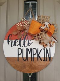 "Hello Pumpkin fall welcome sign/door hanger. This door hanger is the perfect addition to your fall themed indoor or outdoor decor! Each sign is hand made - cut, stained, painted, sealed, and decorated. Comes with a string attached to the back for easy hanging. There are 2 size options - 12\" or 15\", each are 1/4\" thick. Greenery and Ribbons/patterns on ribbon may vary slightly depending on availability. All wood pieces are unique, and may contain slight imperfections as well."