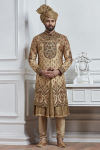 Rich as well as classy look in wedding with this beige color silk fabric sherwani. Smarty features with heavy golden embroidery work at over all, stand collar and full sleeves. Paired with plain kurta and churidar.