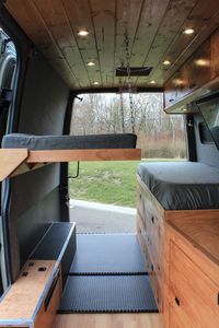 In this converted 2017 Mercedes-Benz Sprinter, a fold-down bed is securely lowered onto chains for the second explorer. The bed can be folded and secured to the wall to open up interior space. #van #vanlife #sprinter #sprintervan #convertedvan #vanconversion #tinyhouse #tinyliving #offgrid #interior #bedroom #freedomvans