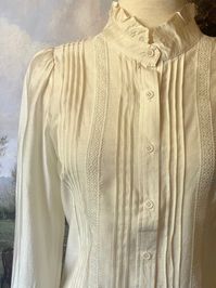 This is the quintessential button-up blouse of the 19th-century, featuring lightweight polished cotton, a high neck ruffled collar, pintuck pleats on the bodice, long button-cuffed sleeves with ruffle hem, and crochet lace trim. Use it as the base of any Victorian or Edwardian era look for tip-top historical accuracy! Sizing: ✧IN Bust Waist Sleeve LxW Length S 38 In. 40 In. 23x14 In. 21 In. M 40 In. 42 In. 23x14 In. 21.5 In. L 42 In. 44 In. 24x15 In. 22 In. XL 44 In. 46 In. 24x15 In. 22.5 In. ✧C