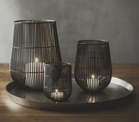 With the look of a bamboo mat, this intricately crafted handmade tealight holder shelters votive candles in a basket of two-toned iron. Its black exterior accentuates the lines, while the gleaming gold interior enhances candlelight's glow. Due to its handcrafted nature, each candle holder will be subtly different.     Handcrafted  100% iron with powdercoat finish  Accommodates standard votive or tealight candle (sold separately)  Wipe with damp cloth  Made in India