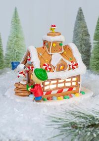 Christmastime is here, and you can spread happiness and cheer in your home with this Peanuts Gingerbread House Tablepiece! This tablepiece features Charlie Brown and Snoopy decorating an adorable gingerbread house.