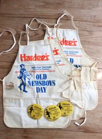 Apron measures 19 1/2 inches tall x 15 inches wide. Aprons are deadstock, crispy (never been washed). Condition is good, with discoloring from age.  Weathered cream colored apron with original bright orange Hardee's logo and blue Old Newsboy Day graphics.  Listing is for one apron, each apron comes with a yellow button!  3 aprons available.