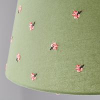 * Green Flower Design * Embroidered Detailing * Reversible Gimbal - Suitable for Ceiling, Floor, & Table Lamps Illuminate your space with the Green Flower Embroidered Tapered Lamp Shade. The delicate green flower design with embroidered details adds a touch of nature to your lighting, and the reversible gimbal makes it suitable for ceiling, floor, and table lamps – a versatile and charming addition to any room.