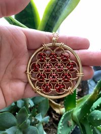 "This necklace features a flower of life pendant with a pink heart in the center. The chain is jeweler's brass and is 20\" in length. The pendant is 2\" in diameter."