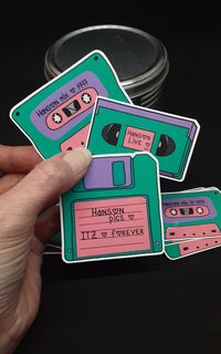 "Get nostalgic with this adorable 90s media sticker set! Each sticker was hand drawn by me ❤️ Hanson VHS mix Hanson cassette tape Hanson floppy disk 2.5\" die cut Waterproof: yes UV safe: INDOOR USE These stickers are completely handmade by me! They have a protective semi gloss coating to prevent scratching! Application: Thoroughly clean and allow area to dry before applying the sticker to a surface. These stickers are perfect to decorate planners, journals, laptops, cars and anywhere else you'd