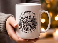 Add a touch of gothic charm to your coffee routine with this unique mug featuring a striking skeleton holding a coffee cup, surrounded by roses and stars, with the playful quote "If I Had Feelings, They'd Be For You". This high-quality ceramic mug is perfect for daily use or as a special gift for the skeleton and gothic art lover in your life. Dishwasher and microwave safe.