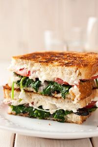 This grilled cheese sandwich is packed with mozzarella, feta, spinach, olives, basil, tomatoes and red onions.