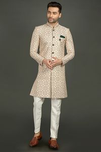 Cotton silk fabric cream hued indowestern for wedding and party ceremonies, Decorated with resham, sequins, embroidered work through out the attire. It has stand collar, full button placket, full sleeves, welt pocket with pocket tie, and vented hemline. Comes with pant.