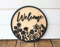 "This wildflower \"Welcome\" sign makes a great housewarming gift, and adds a beautiful touch to any home decor! There are many uses for this sign - classroom, office, tier tray, entryway, or door hanger just to name a few! Item Details: - Made from 2 layers of 1/4 inch birch wood. - Wildflowers are laser cut. - Background wood can be stained any of our stain color choices (sign pictured here is Natural unstained). Wildflowers and \"Welcome\" can be any color of your choice. The flowers and \"we