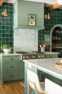 Designed by @rebeccagibbs.design, this fresh green kitchen feels timeless and trend-forward with sage cabinets and a glossy emerald tile backsplash. Our timeless Clemente Wall Lights by AERIN add a beautiful touch of brass. Visit the link to see more colorful designs like this one. 📷: The Good Things