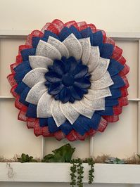 This is a very full multi-layered patriotic wreath. Made on a wreathing board, there are three generous rows of poly burlap. The outside layer of petals is a red plaid poly burlap, the middle layer is a royal blue poly burlap and the inner most layer is white poly burlap with a blue wood flower to complete this beauty. I heat sealed the poly burlap but I also took extra steps to make sure that the burlap will NEVER fray. This beauty can be used for every day use,