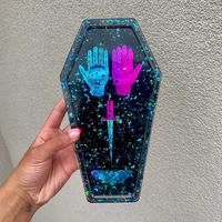 Spooky Resin Coffin Tray made by yours truly, available in my shop now! Made with holographic foil inserts including a palmistry hand, dagger, and moth. Resin, Resin Art, Resin Artist, Trippy Art, Halloween Decor, Spiritual Decor, Home decor, Spiritual, New Age, Moth, Witch Craft, Witch, Wicca, Wiccan, Tarot-cards, Palmistry, Horoscopes, Astrology, Evil Eye, lunar moth, moon, lunar, moonphase, fall vibes, gothic, gothic art, holographic art, spooky vibes, halloween vibes, small business, etsy